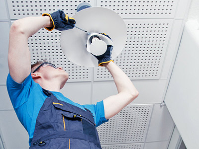 Ein Mann, der eine Deckenlampe installiert oder repariert.